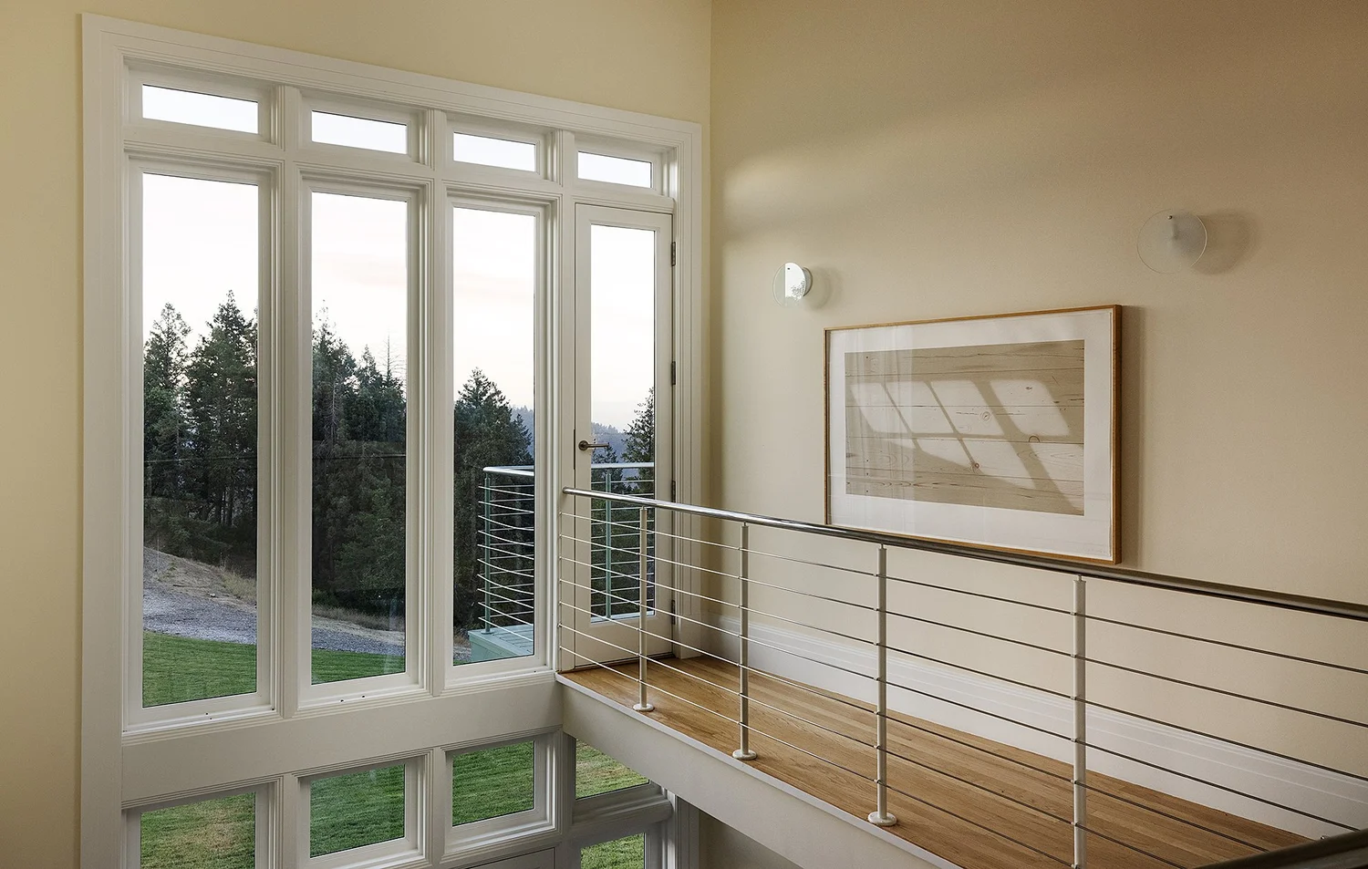 Upper landing with tall windows, railings, and woodland views